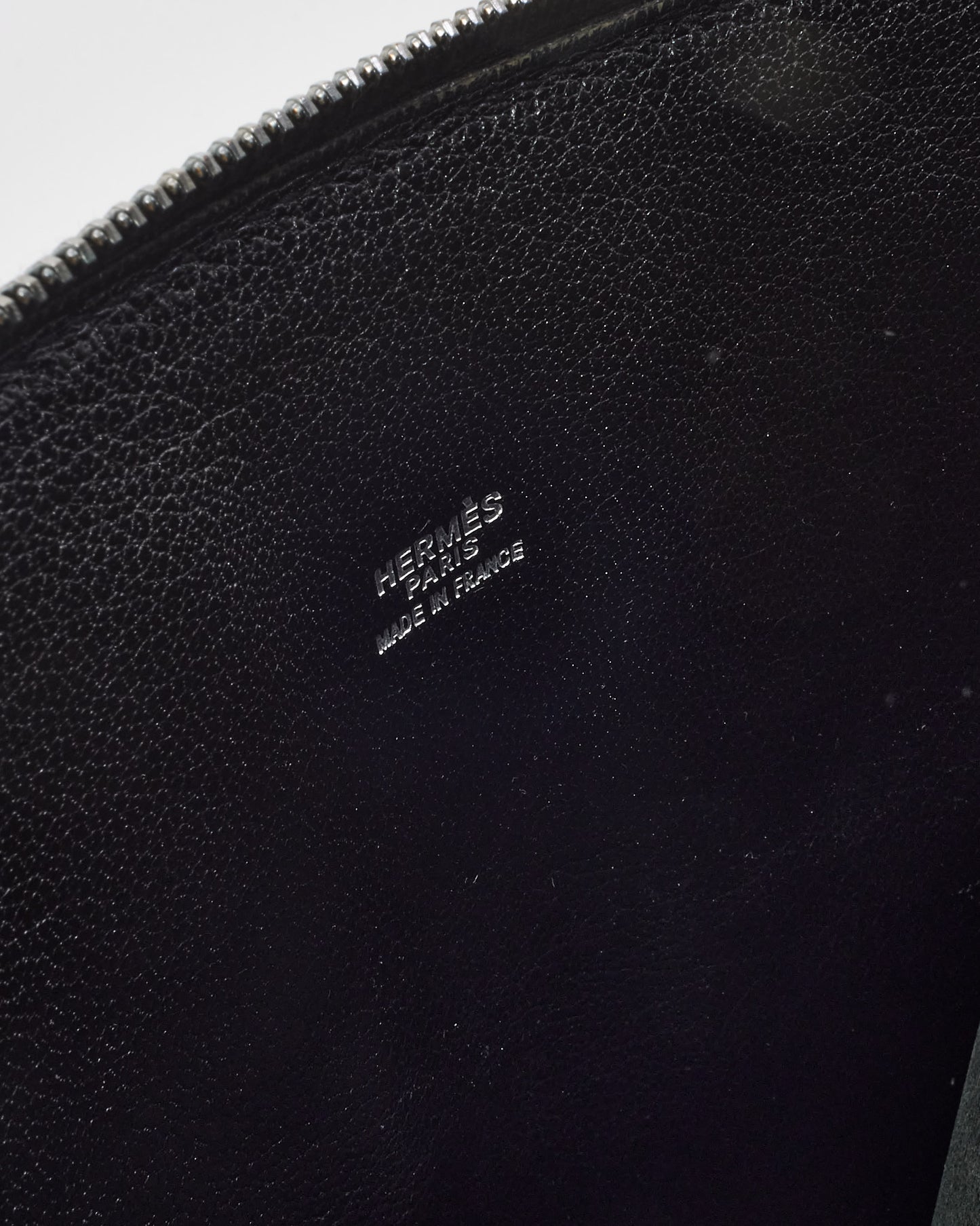 Close-up of a black leather Hermès pouch with visible branding.