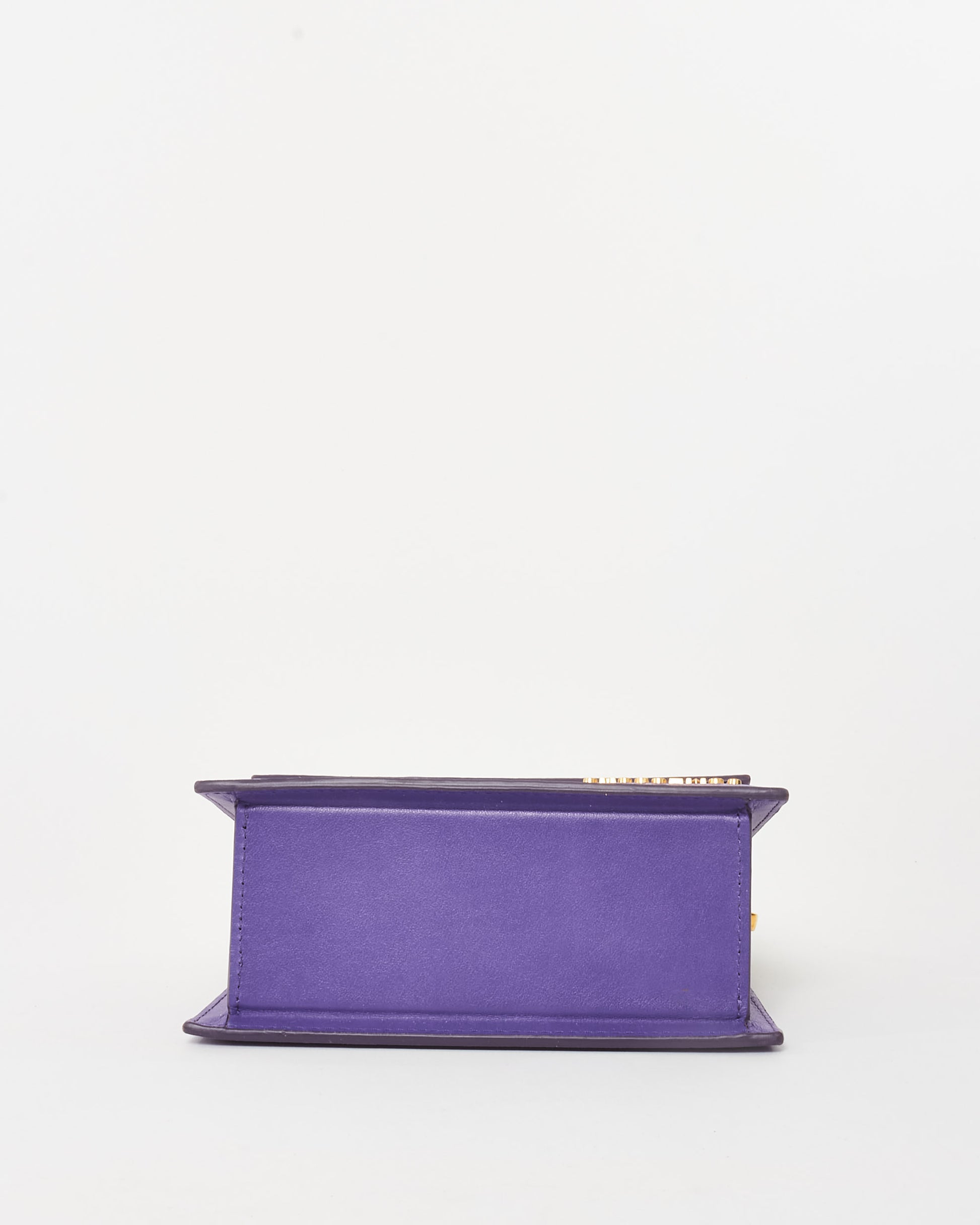 Jacquemus Le Chiquito Noeud mini handbag in vibrant violet leather, featuring a structured trapezoidal silhouette, circular top handles, and gold-tone logo detailing, bottom view.