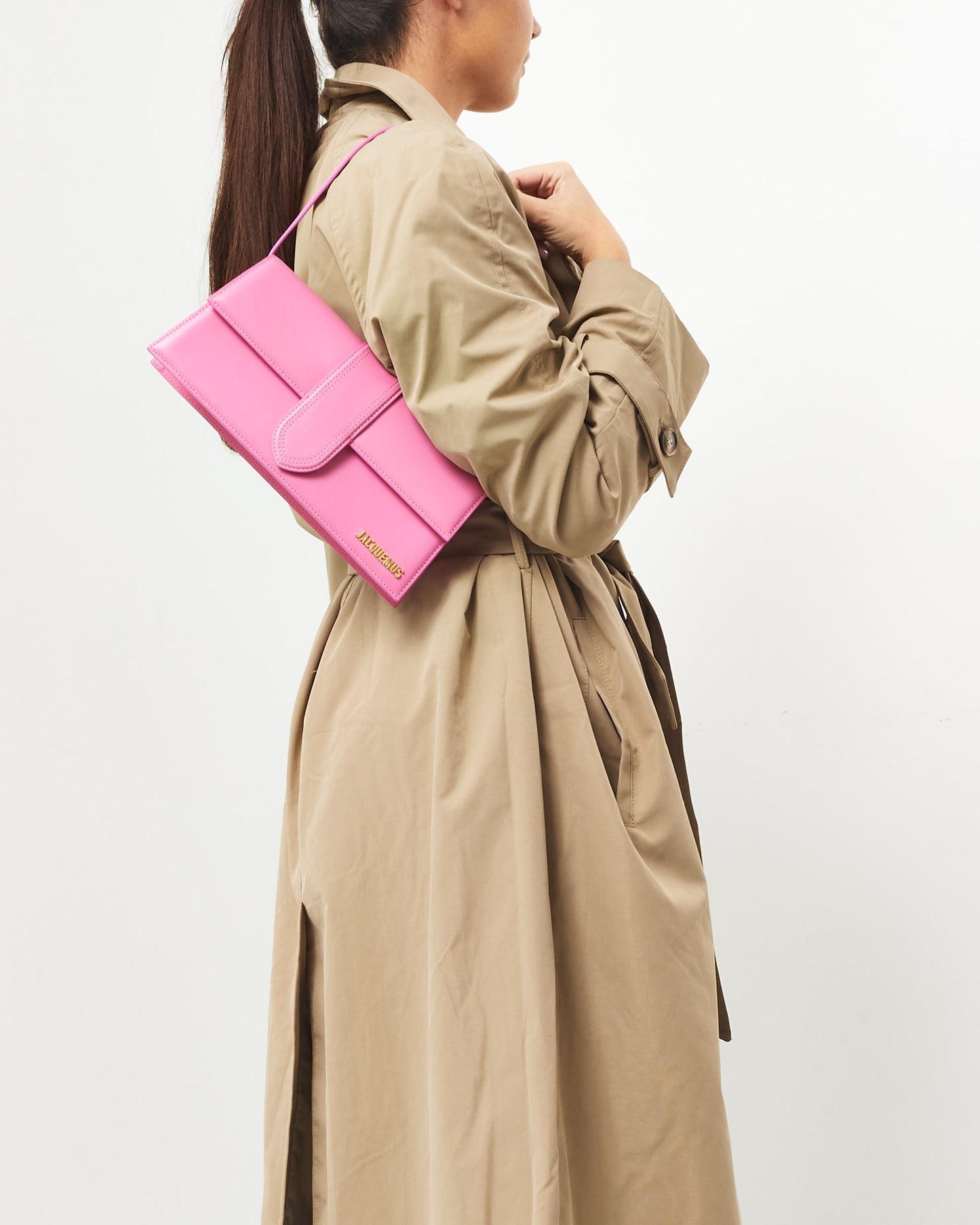 Pre-owned Jacquemus Le Bambino Long bag in soft pink leather, featuring a sleek rectangular silhouette, an extended front flap with tonal stitching, a thin shoulder strap, and gold-tone Jacquemus logo, on shoulder.