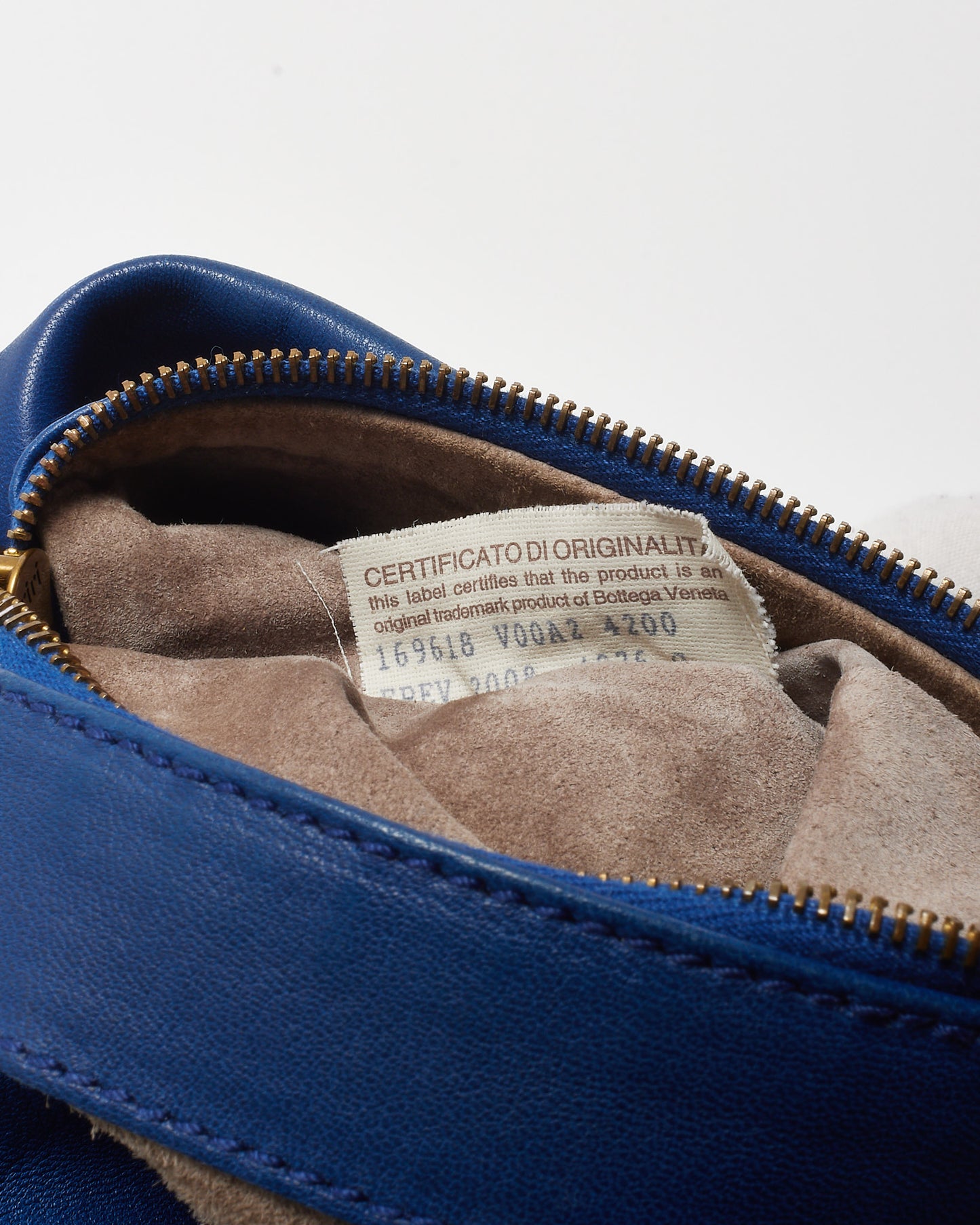 Blue leather Bottega Veneta product with a visible authenticity label on a white background 