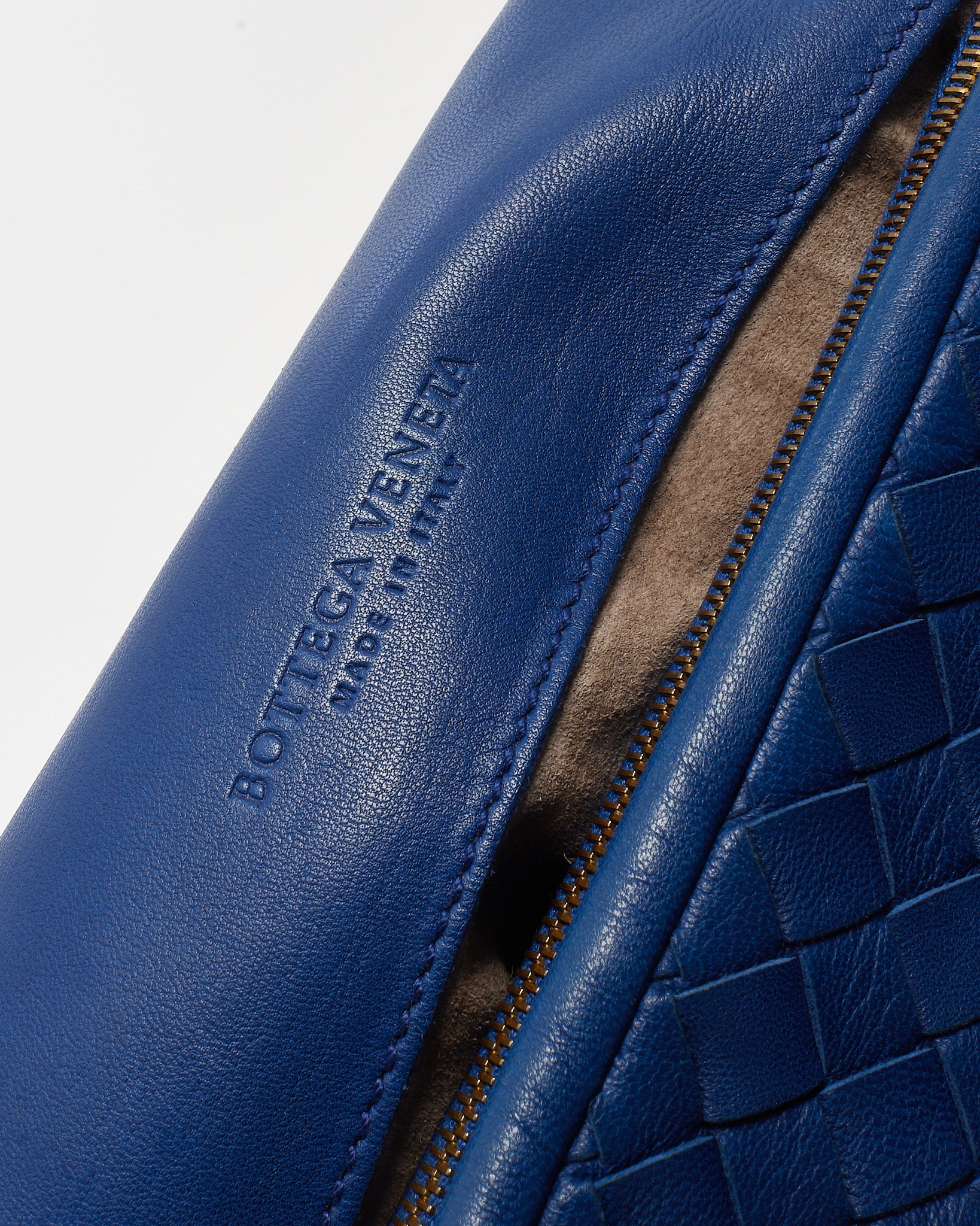 Close-up of a blue leather product with Bottega Veneta branding on a light gray background