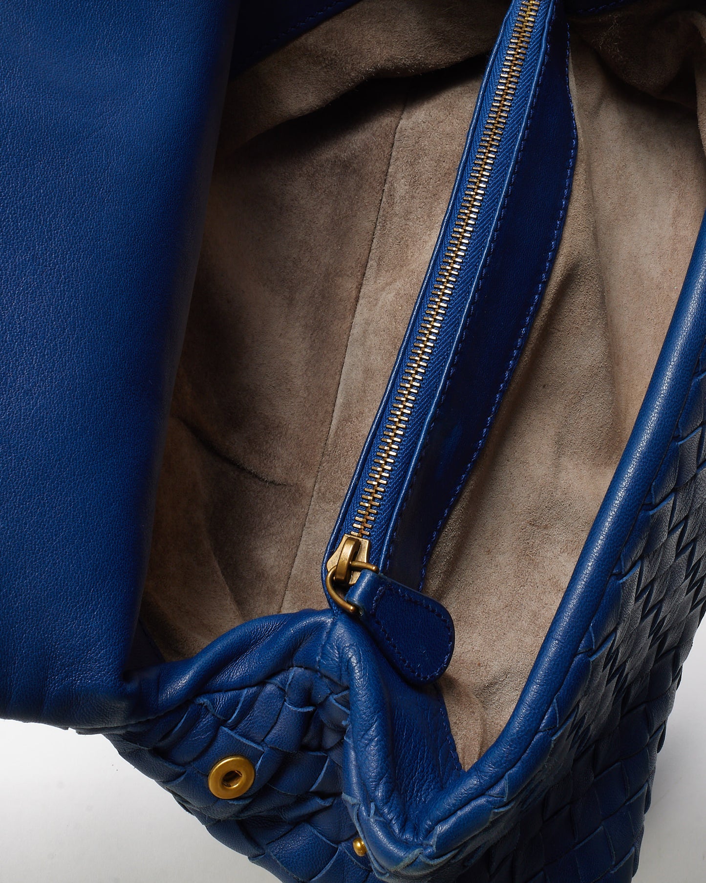 Close-up of a blue leather handbag with gold zipper and hardware.