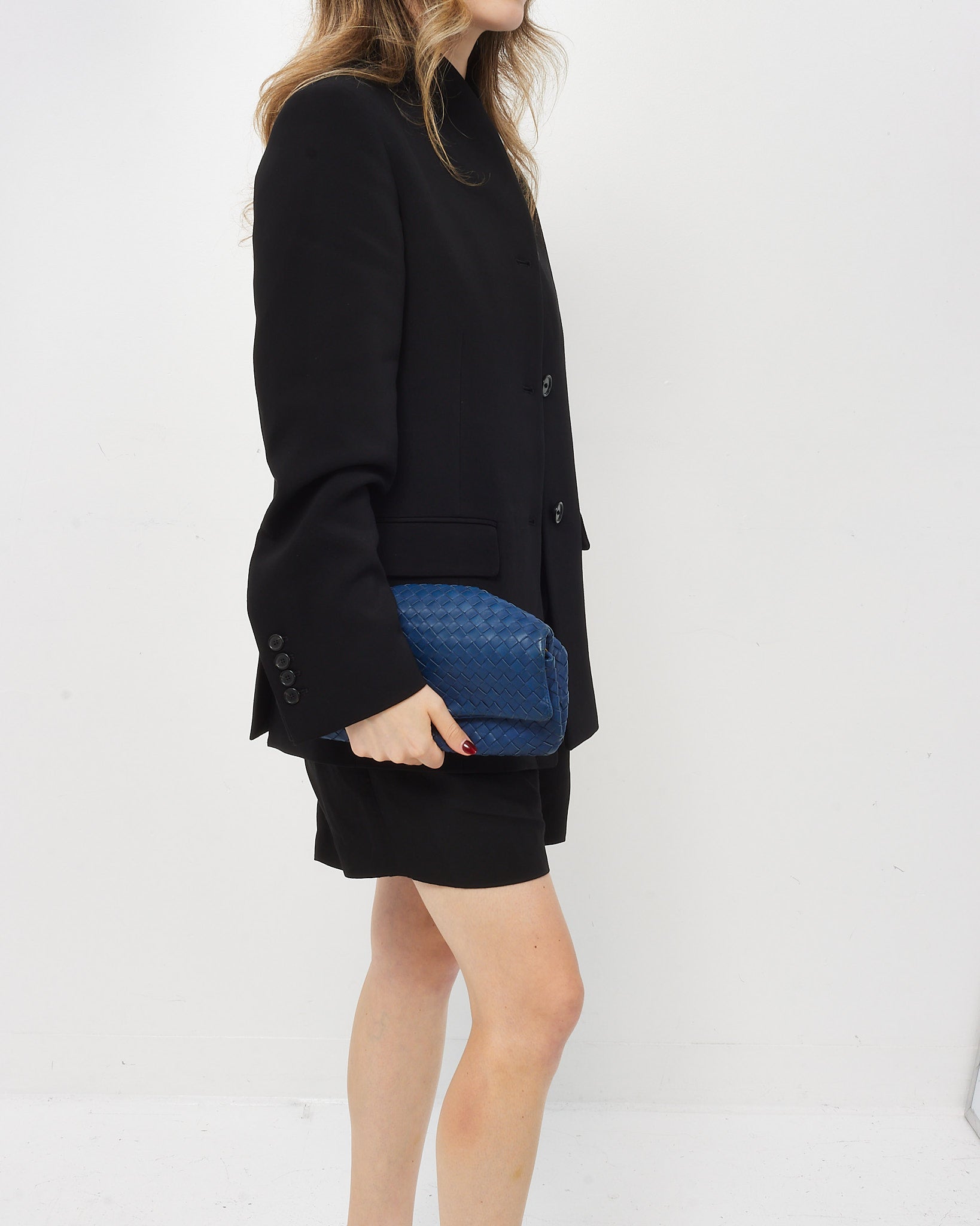 Person holding a Bottega Veneta Blue woven clutch bag on a white background
